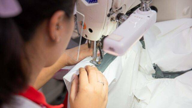 Costurera de Hi-Tech cosiendo tela blanca en la máquina de coser