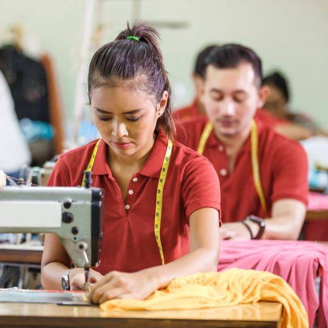 Sewing operators wearing red polo shirts in a garment factory