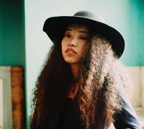 Young women with curly hair wearing black hat and suit