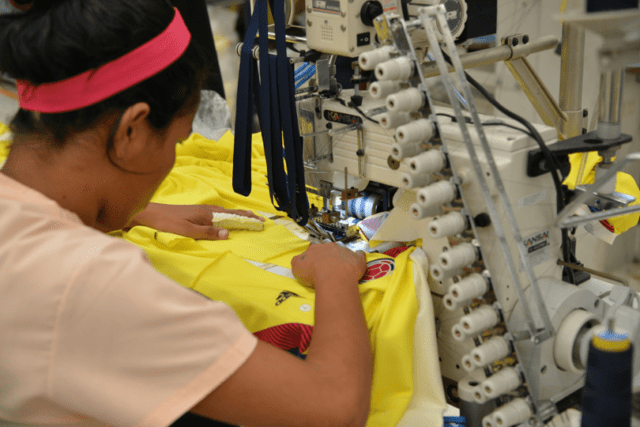 Female garment sewing operator stitching an Adidas jersey in Supertex factory