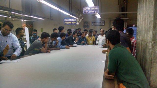 A group of people discussing on the cutting floor of a garment factory
