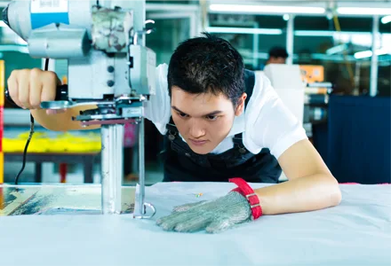 Fabric cutting operator wearing safety glove in a garment factory